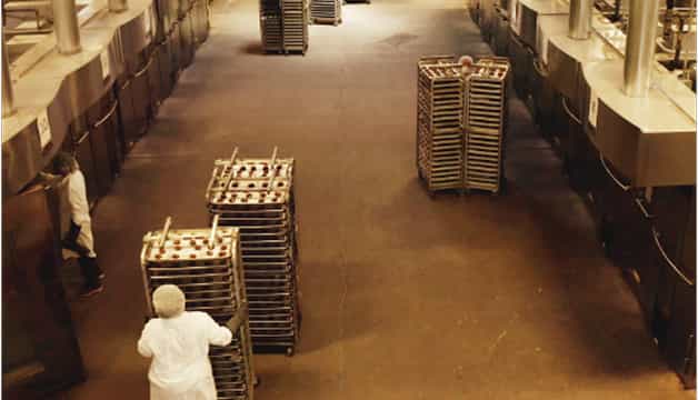 Inside Jimmy's Gourmet Bakery, workers moving racks of baked goods